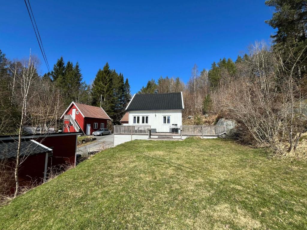 a white house with a red barn and a yard at Snemyr i Høvåg in Høvåg