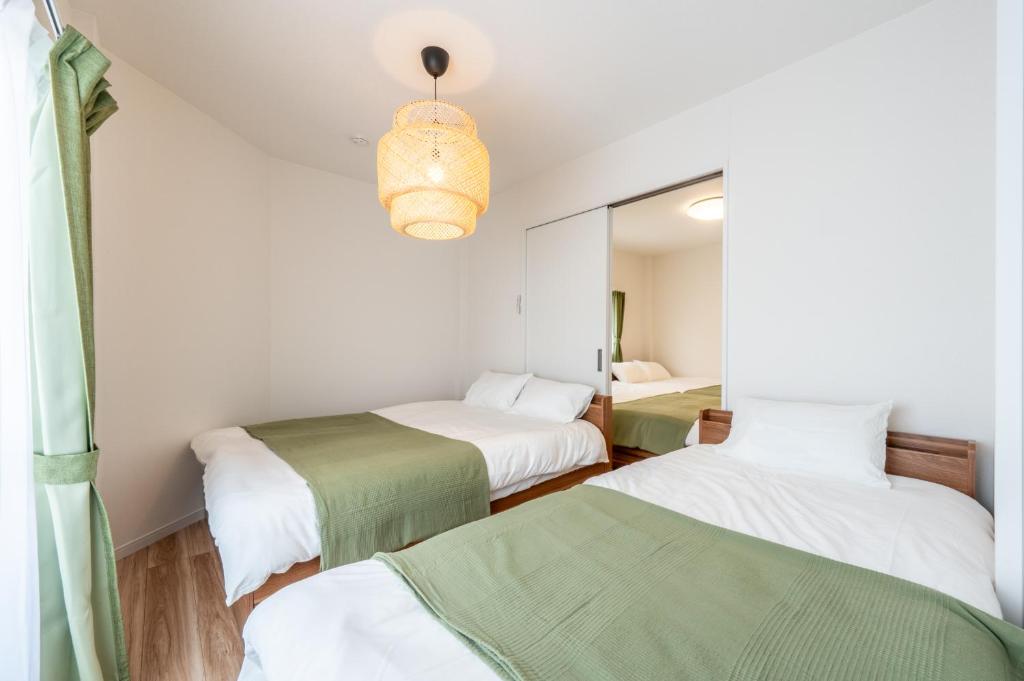 a room with three beds and a mirror at 3 Free Rental Bicycles - Free Parking - 85sqm - Up to 9 Guests - 7min to Koreatown - Japanese Lessons by Professional teacher - 自転車3台無料貸出 - 無料駐車場 - 85平米 - 定員9名 - コリアタウン徒歩7分 - Mintak Katsuyama V Residence in Osaka