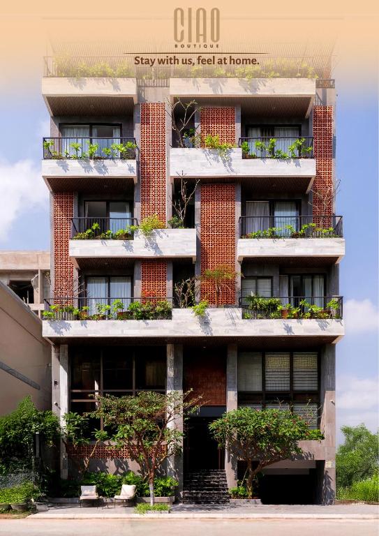 a tall brick building with plants on the balconies at Ciao Boutique Danang - New Hotel Opening April 2026 in Danang