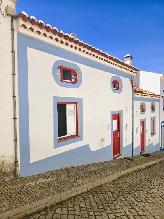 a blue and white building with red doors on a street at Casa Pedra da Foz in Odeceixe