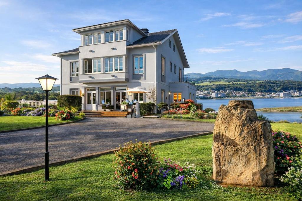 a large white house with a large rock at Hotel Capellan in Navia