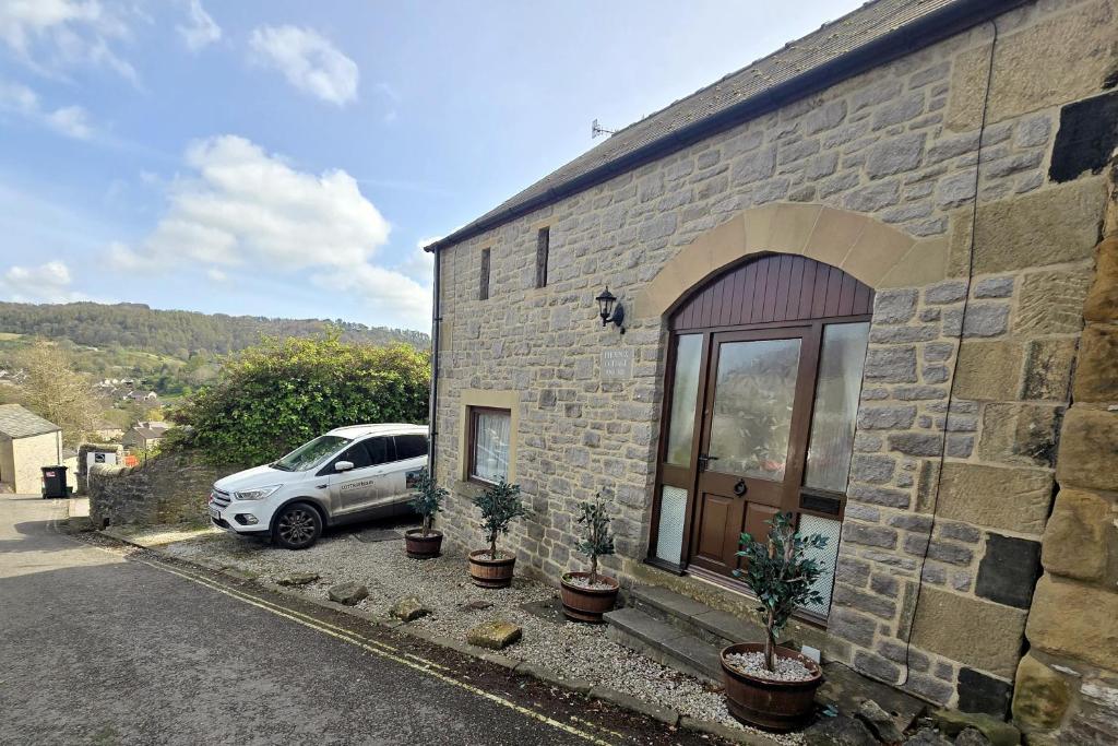 a car parked next to a stone building with plants at Phoenix Cottage, Bakewell in Bakewell