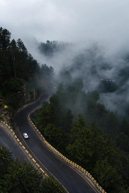a winding road with a car driving down a mountain at Nathia Lodge Cottage in Nathia Gali