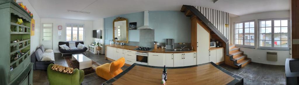 a large living room with a kitchen and a staircase at L'Atelier du Tailleur à 5 mn du Puy du Fou in Chambretaud