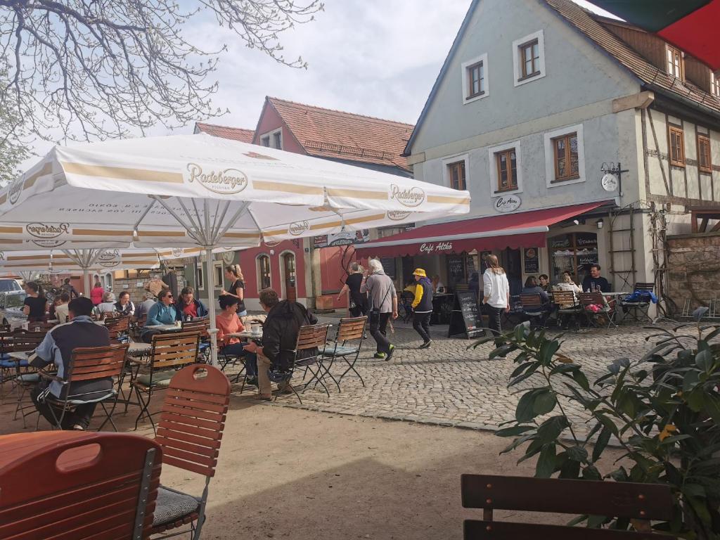 a group of people sitting at tables and umbrellas on a street at FEWO Radebeul Am Waldrand Spittelholz in Radebeul