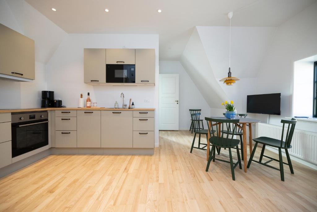 a kitchen with white cabinets and a table and chairs at Lønstrup Apartments, Klitrose in Lønstrup