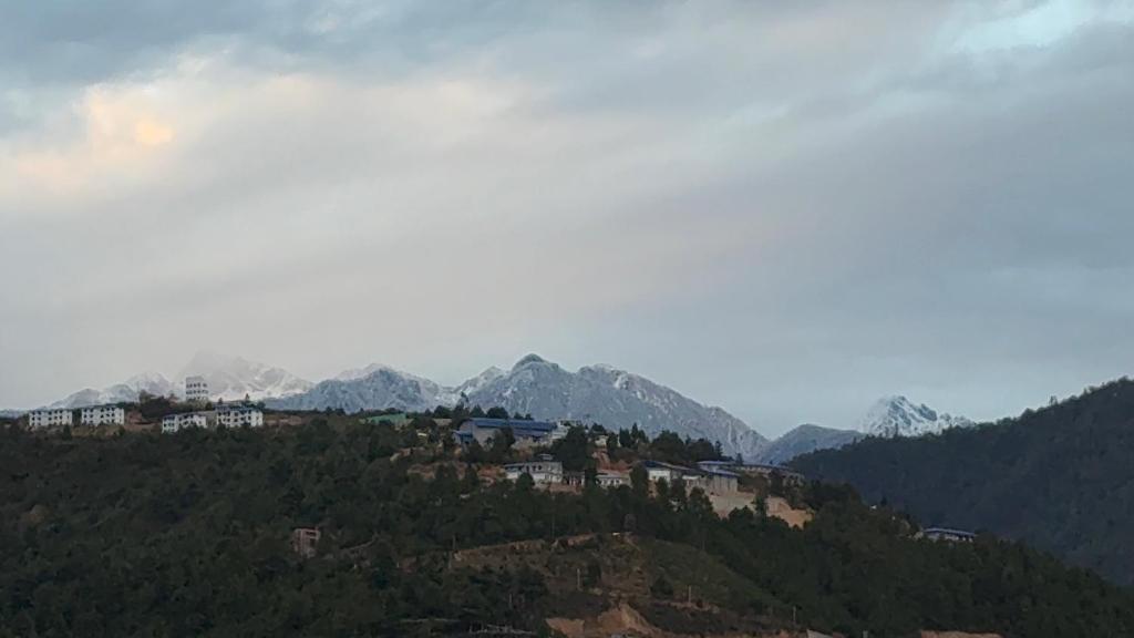 a town on a hill with mountains in the background at E-RE House, Dirang in Dirang Dzong