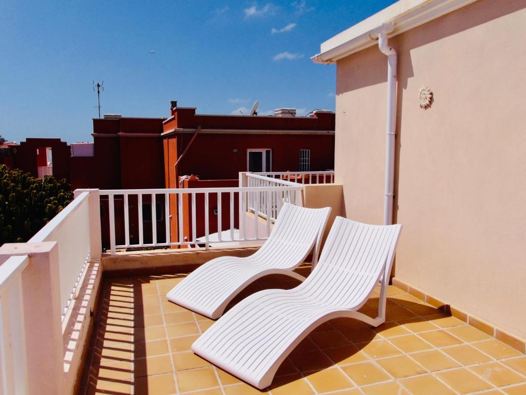 two white chairs sitting on top of a balcony at Casita Playa Castillo 5 in Caleta De Fuste