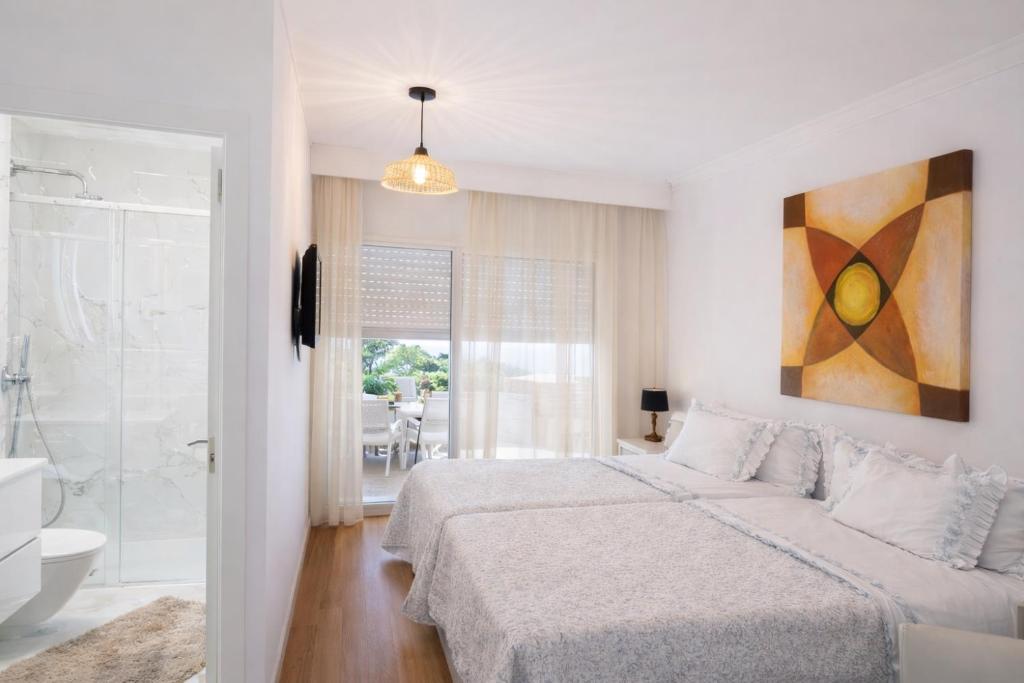 a white bedroom with a bed and a bathroom at City World Apartment in Maia
