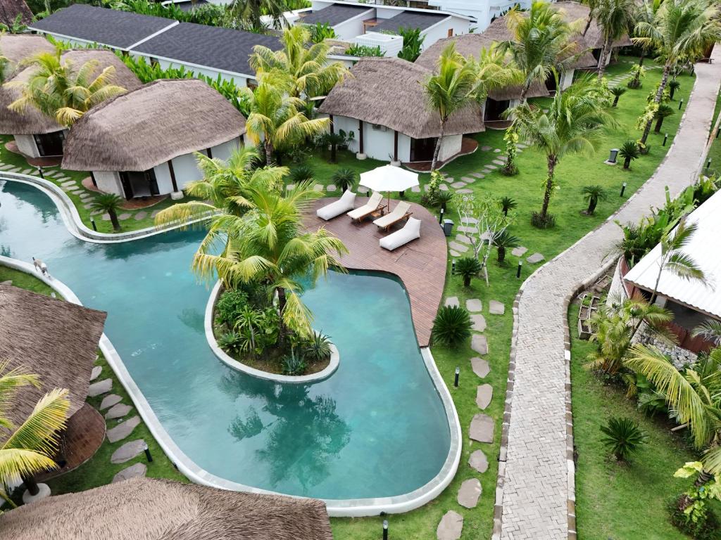 an overhead view of a resort swimming pool with chaises and palm trees at enn Collection in Kuta Lombok