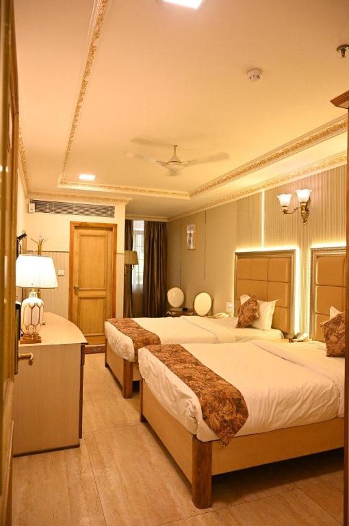 a hotel room with two beds and a desk at HOTEL GALAXY GRAND in Lucknow