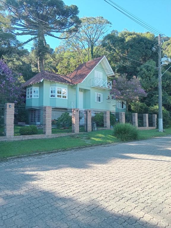 a house on a street with a brick driveway at Casa Verde do Lago in São Francisco de Paula