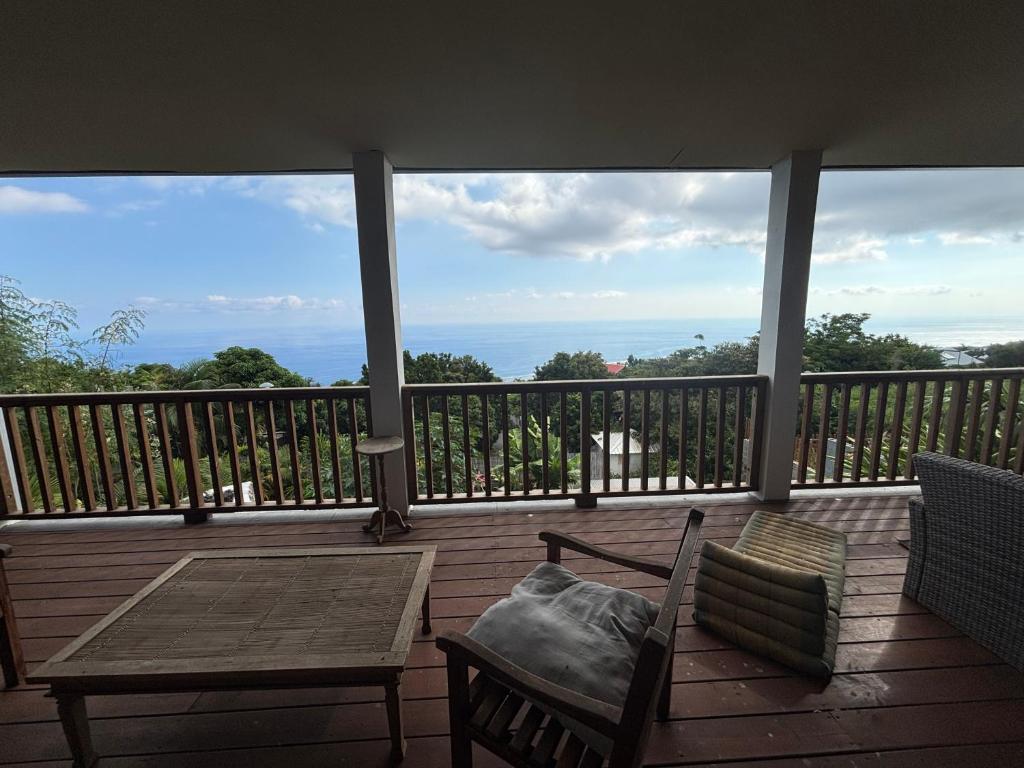 a balcony with a table and chairs and a view of the ocean at Villa Papang in Saint-Paul