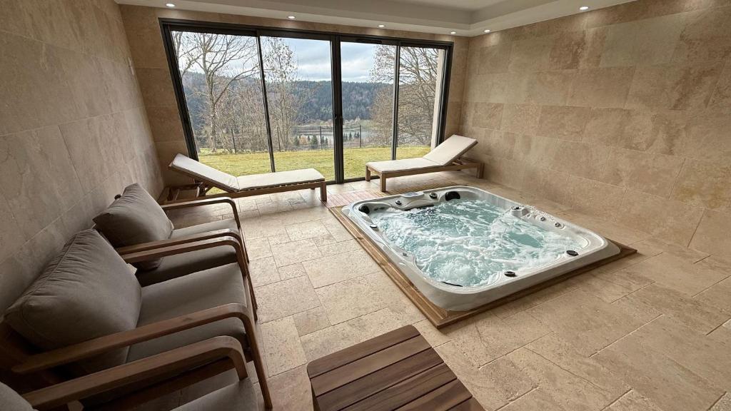 a large jacuzzi tub in a room with a window at La Rose du Lac Hôtel Appart' in Coucouron