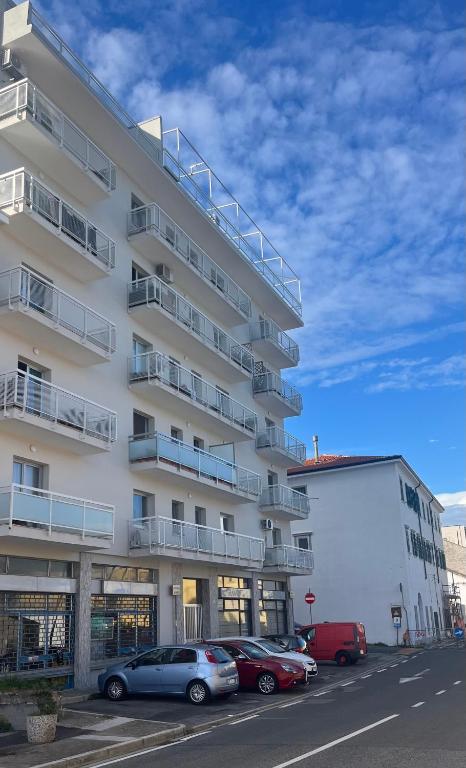 a large white building with cars parked in a parking lot at La dolce vela in Muggia