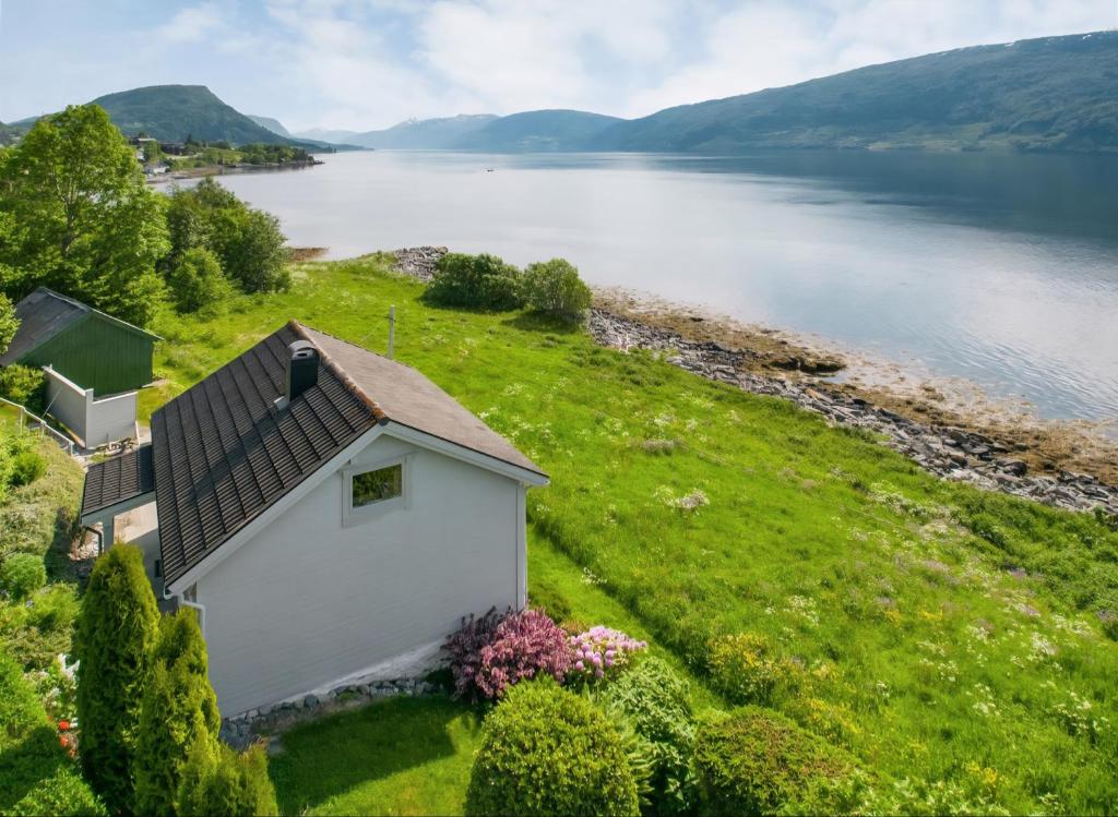 a small white building on a hill next to a body of water at Nordfjord Charm in Stårheim