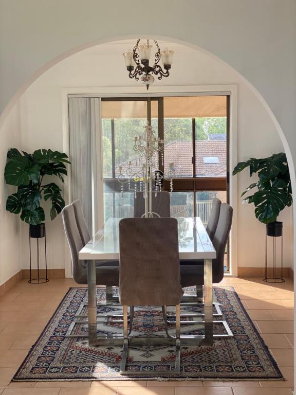 a dining room with a glass table and chairs at Family Haven Bradburry in Campbelltown South
