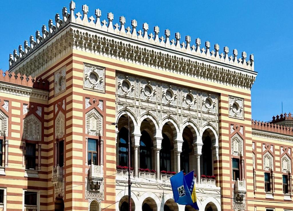 a large building with a flag in front of it at FG Apartment in Sarajevo