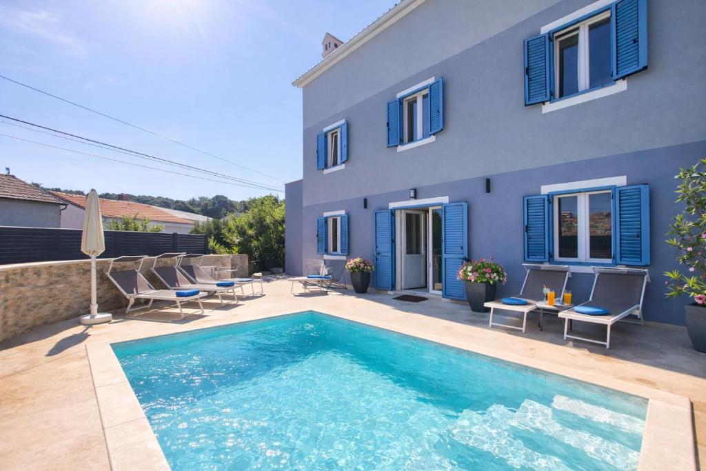 a villa with a swimming pool in front of a house at Casa Solis Losinj in Mali Lošinj