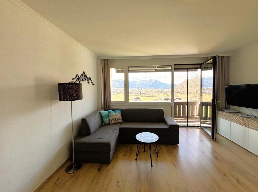 a living room with a couch and a large window at Seestern Strobl in Strobl