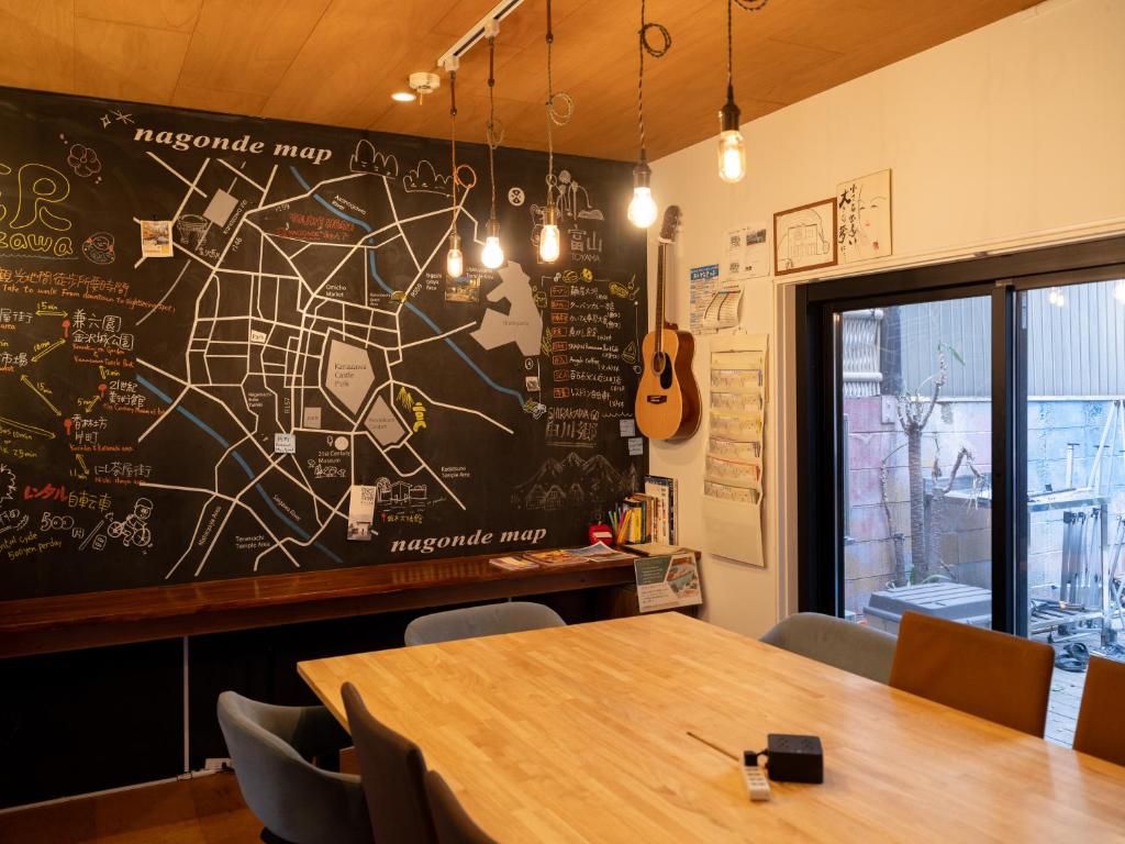 a chalkboard wall in a restaurant with a table and a guitar at Guesthouse Nagonde in Kanazawa