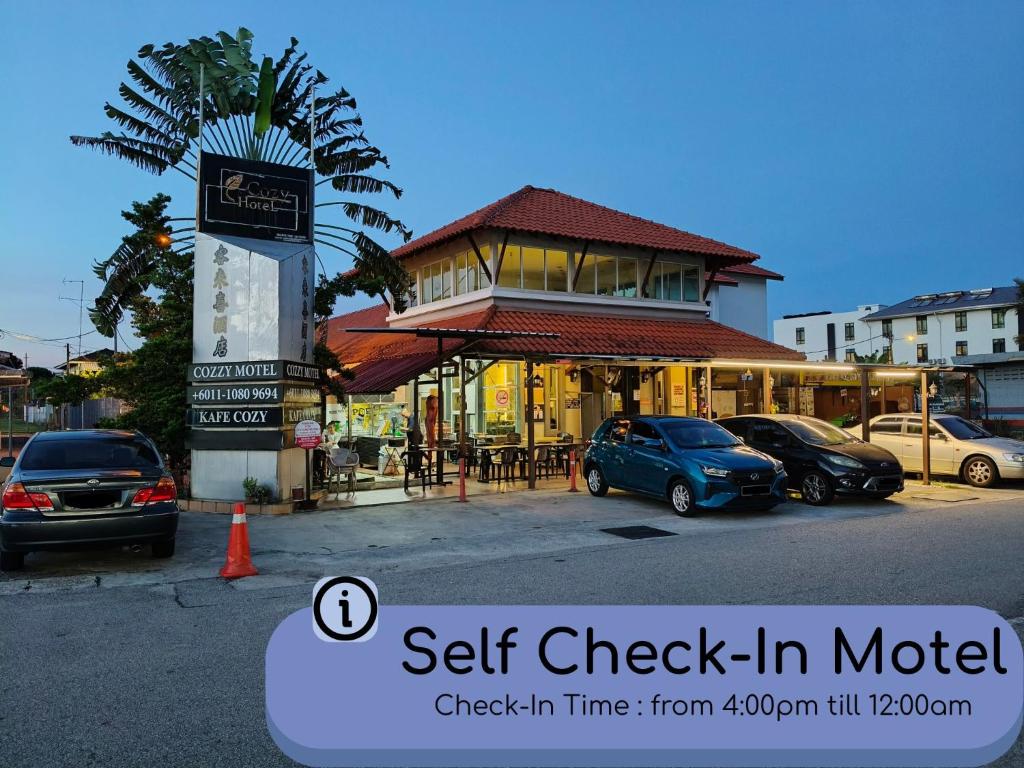 a street with cars parked in front of a building at Cozzy Motel Malacca in Malacca