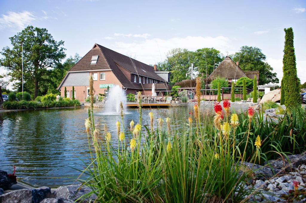 a pond in front of a house with a fountain at Landhaus Eden 3 Sterne Superior in Soltau