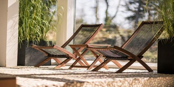 two wooden chairs sitting on a porch with plants at Kysthusene in Gilleleje