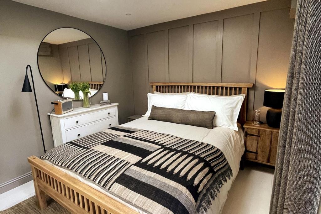 a bedroom with a large bed and a mirror at Studio 77 Cheltenham in Cheltenham