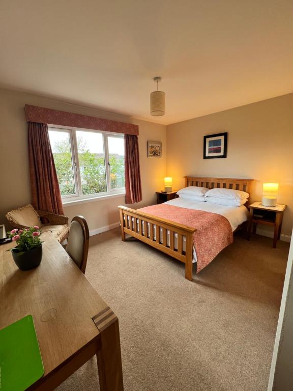 a bedroom with a large bed and a table at The Rowans B&B in Connel