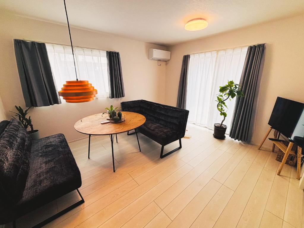 a living room with a couch and a table at 新築一棟貸切 民宿 夢 駐車場2台無料 コンビニ徒歩2分 市街地へ好アクセス in Matsuyama