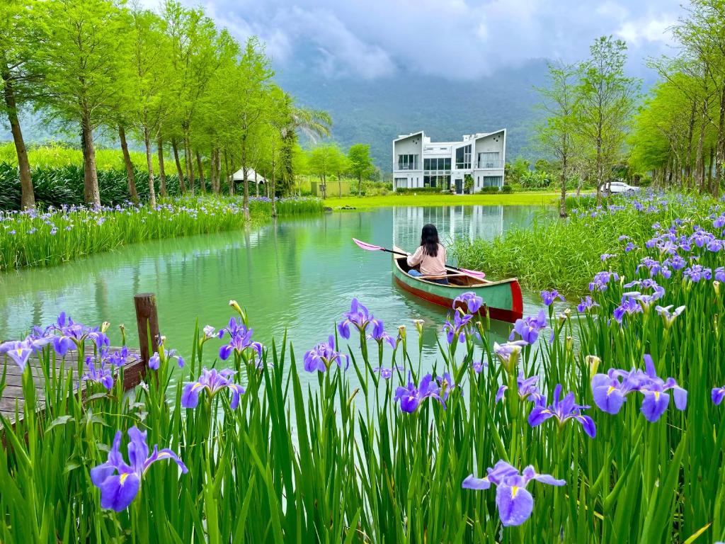 a woman in a boat on a river with flowers at 靜樹湖民宿Jing Shuhu B&B in Shuhu