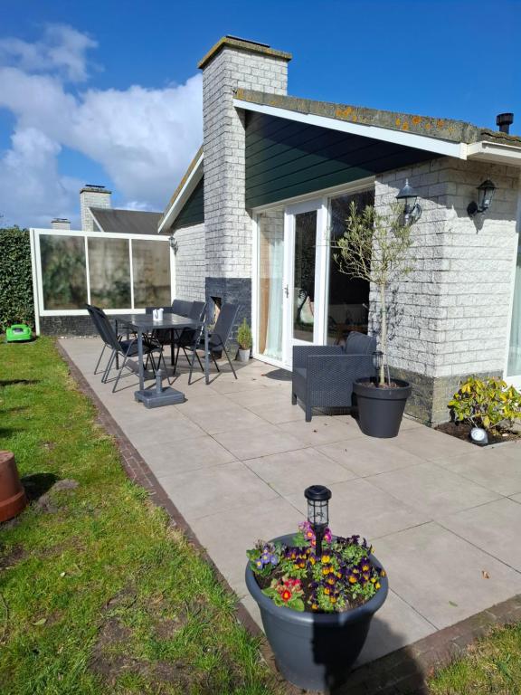 a patio with a table and chairs and flowers at Cosy Petten, Family only in Petten