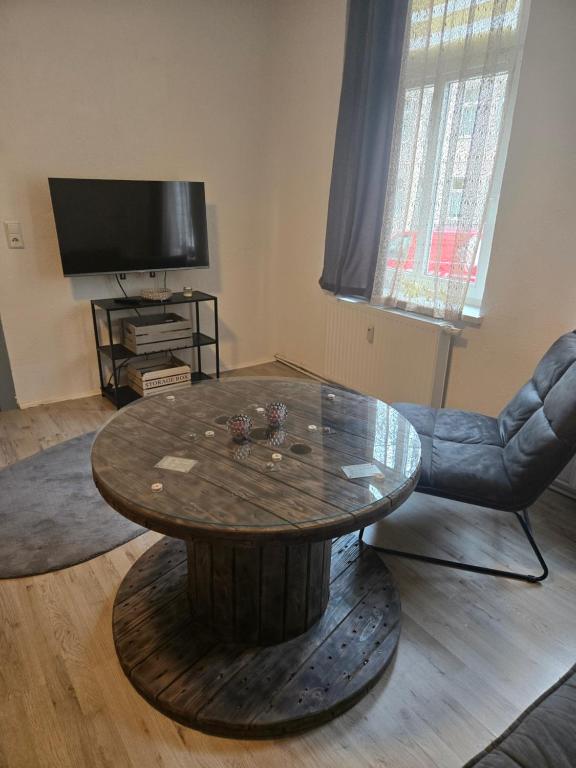 a living room with a wooden table and a television at Ferienwohnung 1 am Bahnhof in Bernburg