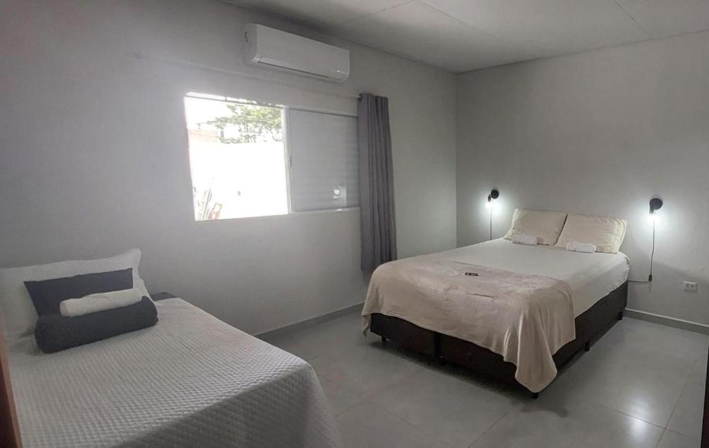 a bedroom with two beds and a window and a chair at Casa de piscina Pôr do Sol in Chapadão do Sul