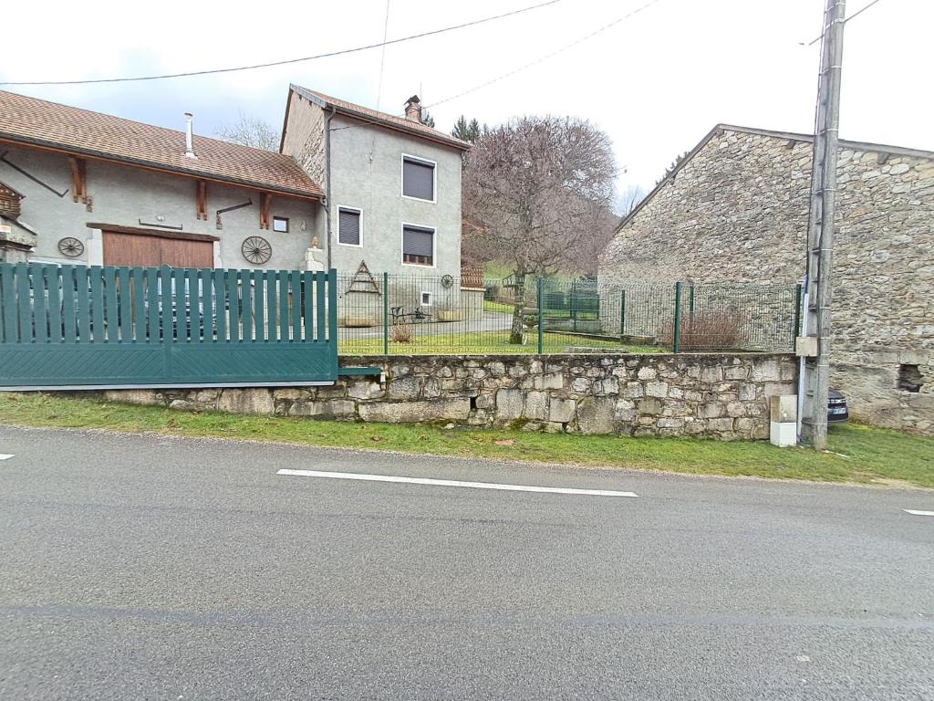 a house with a fence on the side of a street at Gîte "EN VALROMEY" au pied du Grand Colombier in Munet