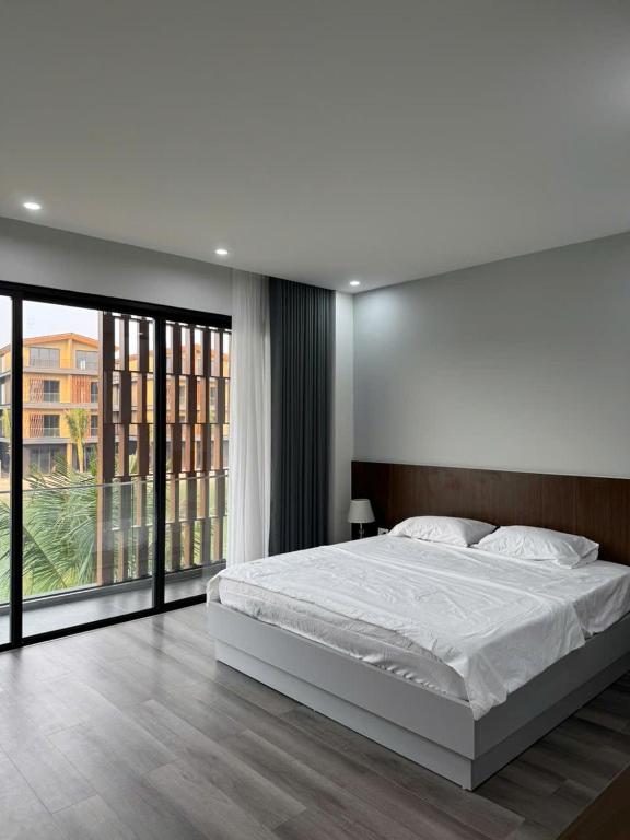 a bedroom with a white bed and a large window at HAHA'S Villa in Binh Hai