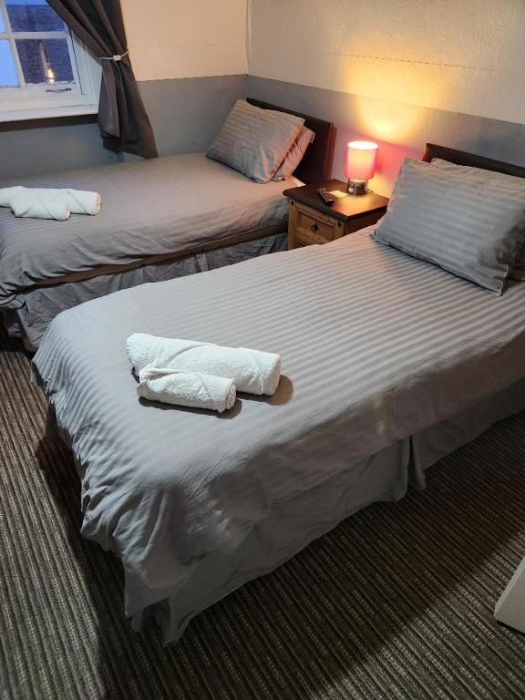 two beds in a hotel room with towels on them at Spalite Hotel in Gloucester