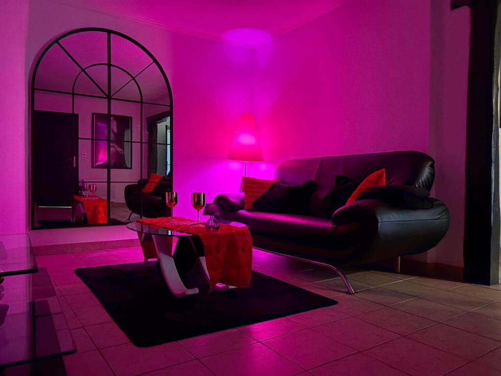 a living room with pink lighting and a couch and a table at maison romantique avec spa privé in Montargis