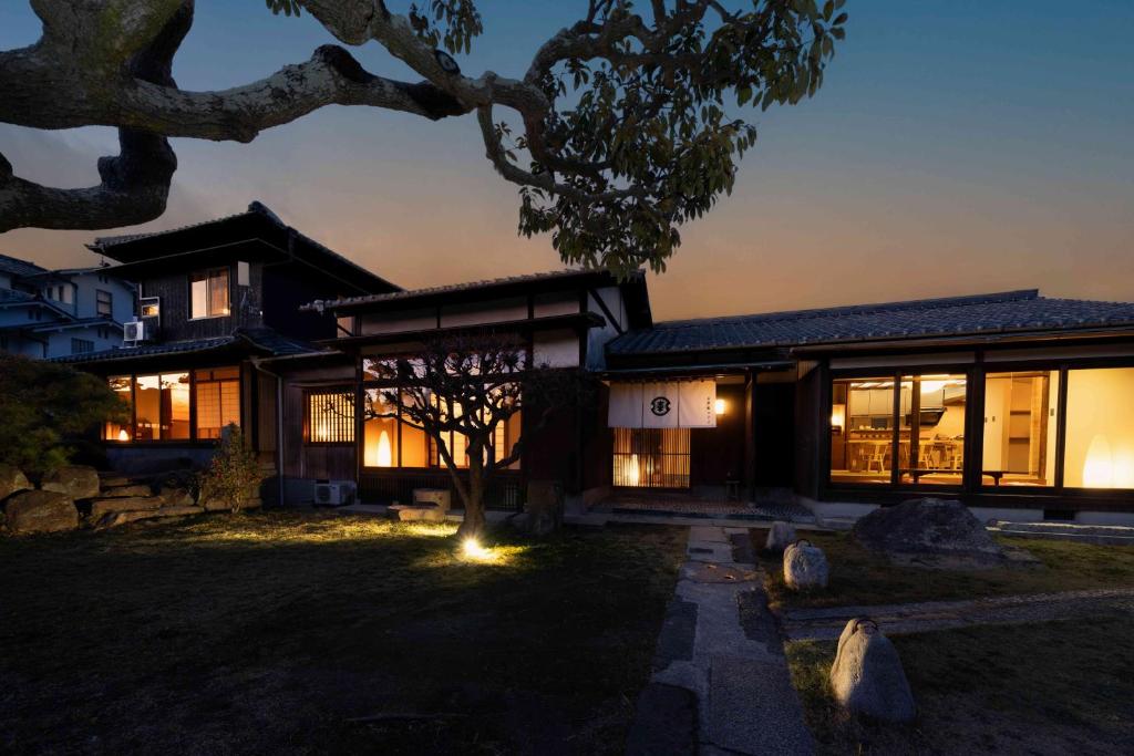 a house with a lot of windows at night at 3000平米の元醤油名家邸宅, 日本庭園, 蔵Bar, サウナ, 出張料理, フルサービスの宿 in Shodoshima