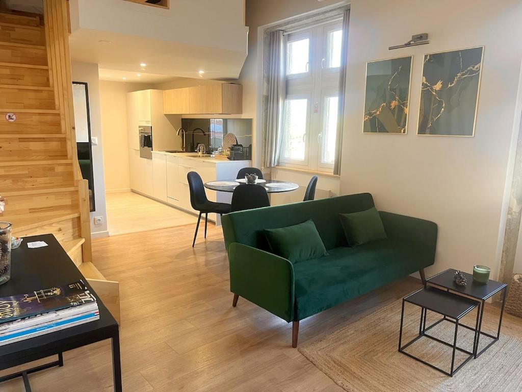 a living room with a green couch and a kitchen at Le Cocon du Mont'Anay in Montanay