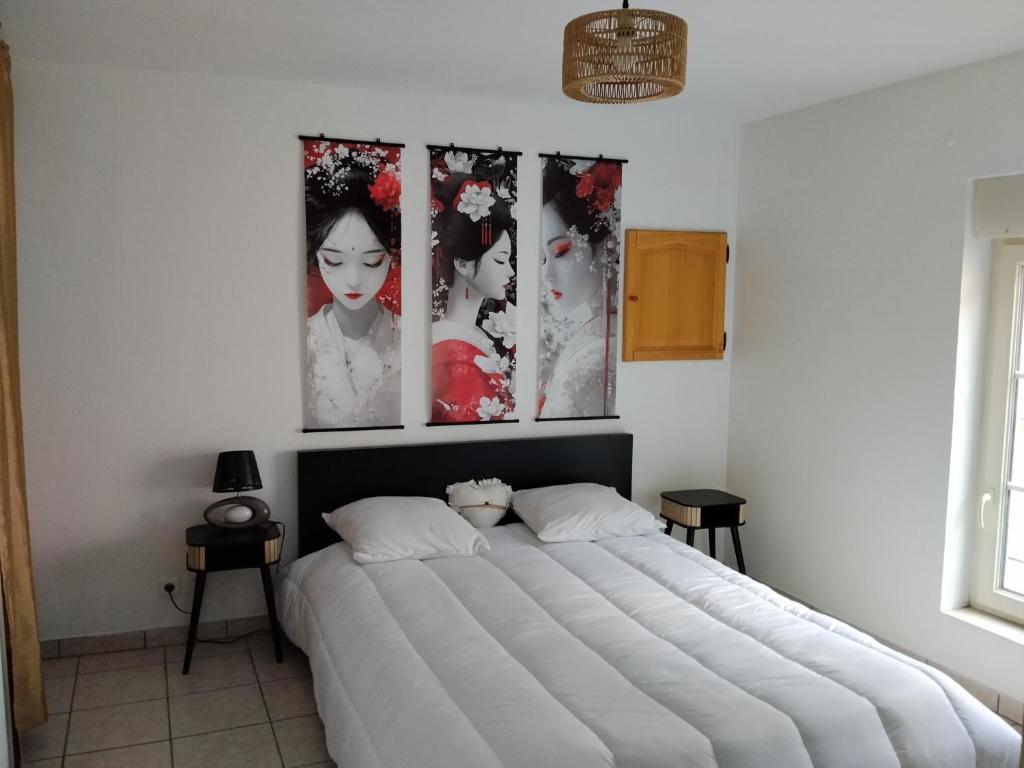 a bed in a bedroom with three pictures on the wall at Yapas in Beaumont-sur-Sarthe