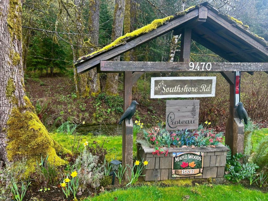 a sign in the middle of a garden with flowers at Maple Woods B&B in Honeymoon Bay