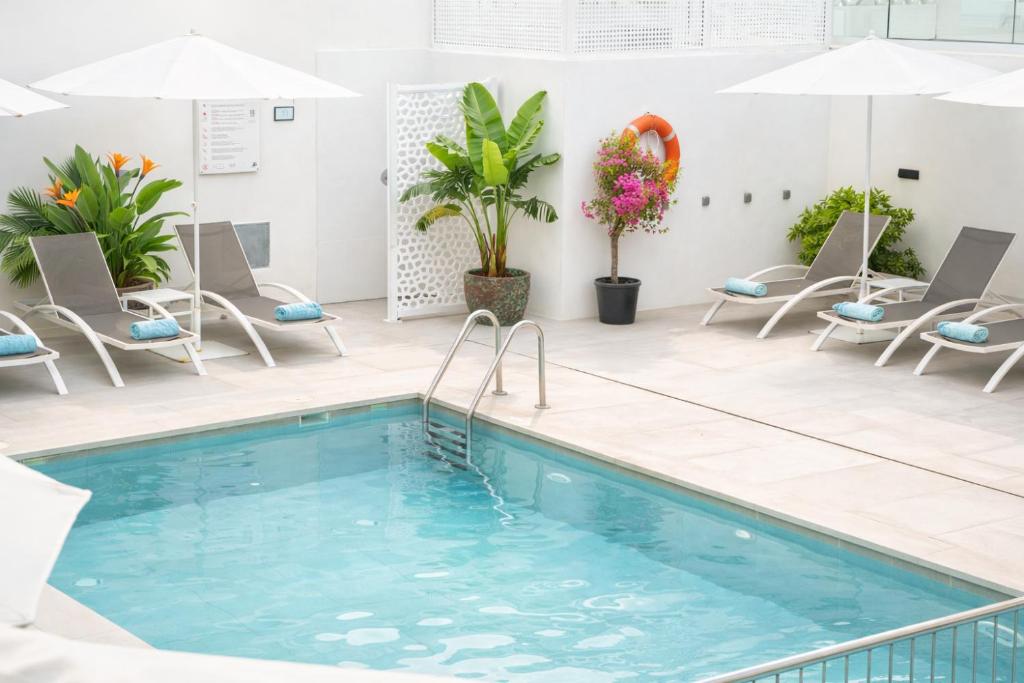 a pool in a hotel with chairs and umbrellas at Aparthotel Marina Drach in Porto Cristo