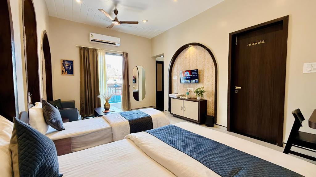 a hotel room with two beds and a mirror at Hotel Omkareshwar Jyotirling Inn in Godarpura