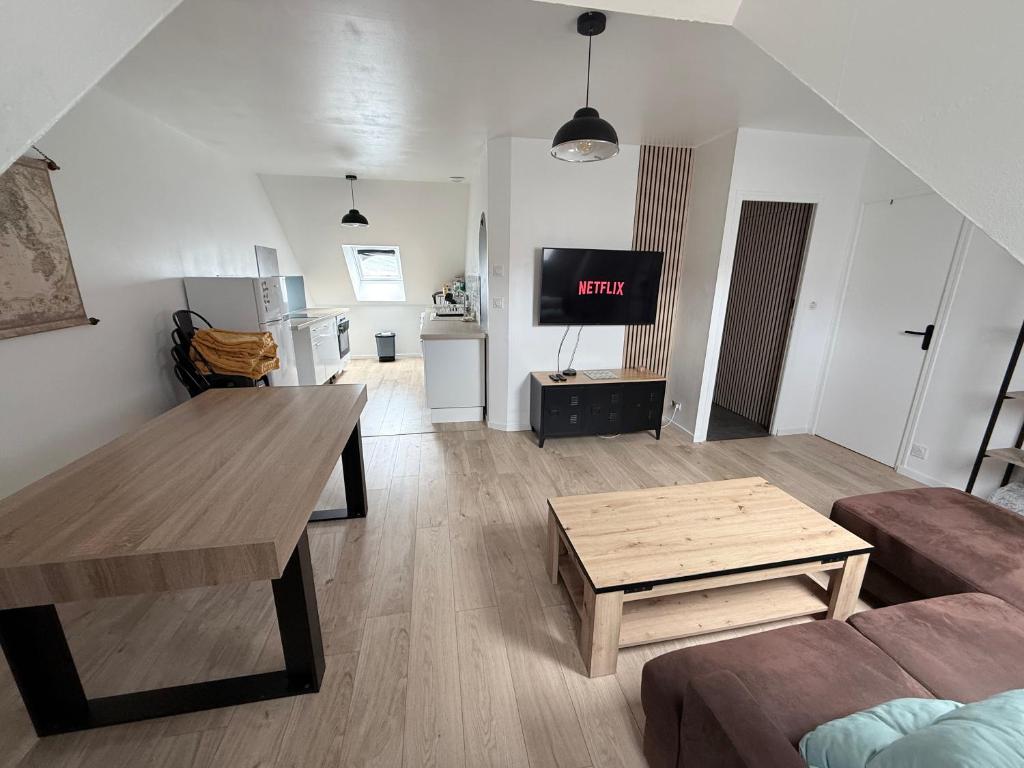 a living room with a couch and a table and a tv at La nouvelle école in Ruillé-en-Champagne