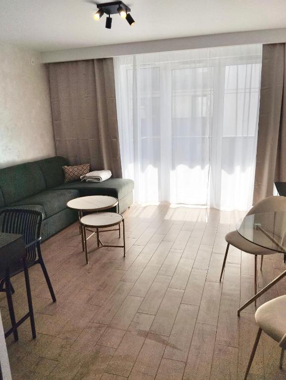 a living room with a green couch and tables at Amazing Studio Close to Oldtown in Gdańsk