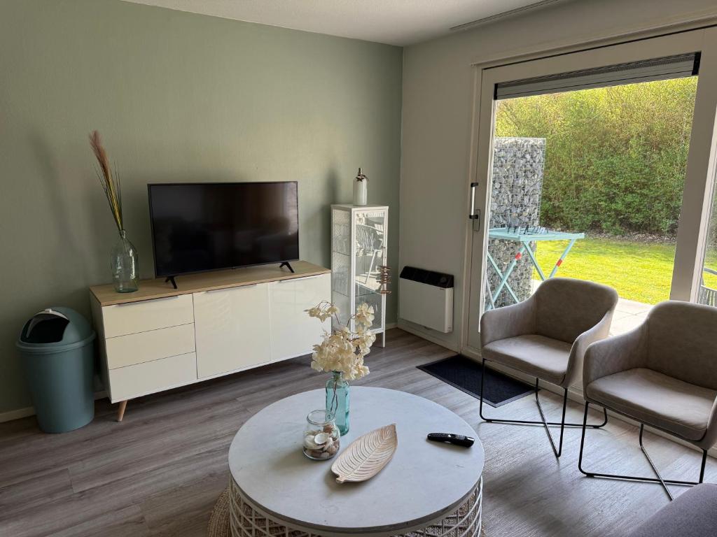 a living room with a television and two chairs and a table at Appartement Noflik, Amelander Kaap in Hollum