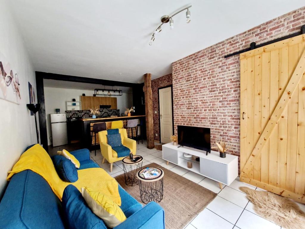 a living room with a blue couch and a brick wall at Cosy atelier in Vierzon