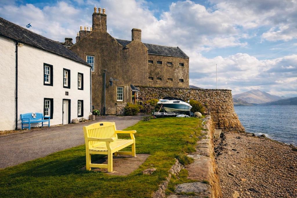 a yellow chair sitting on the grass in front of a castle at Para Handy Cottage, Inveraray in Inveraray